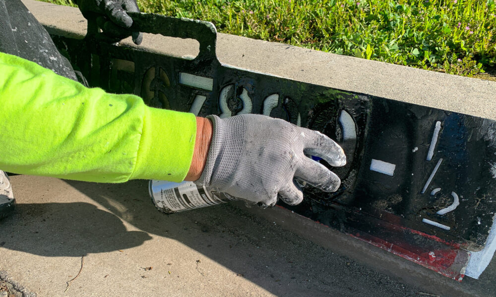 Worker paints address number on curb