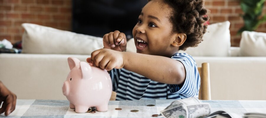 boy putting money in piggy bank