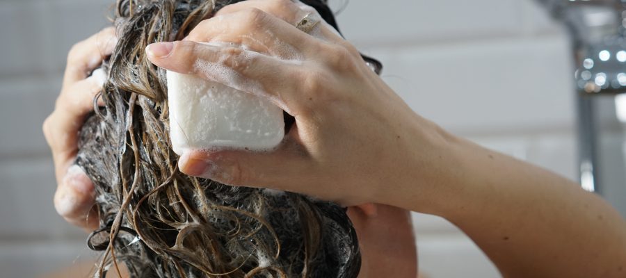 Caucasian woman washes her brown hair with shampoo bar or soap