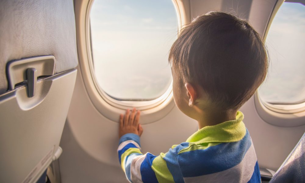 Small child looks out airplane window