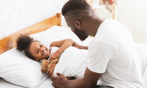 Parent talks to smiling kid in bed