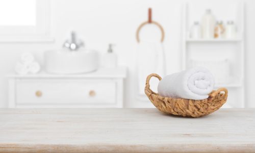 Towel in basket on wooden table in bathroom