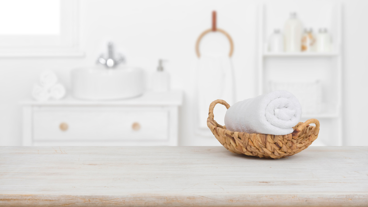 Towel in basket on wooden table in bathroom