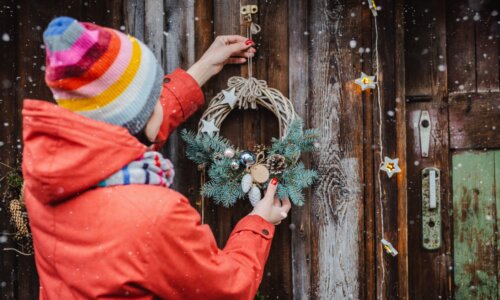 Person hangs twig wreath on door for Christmas holidays