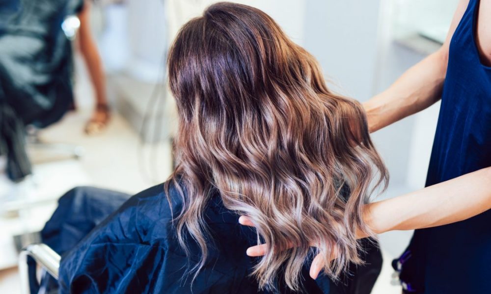 Young woman getting beautiful hairstyle in hair salon.