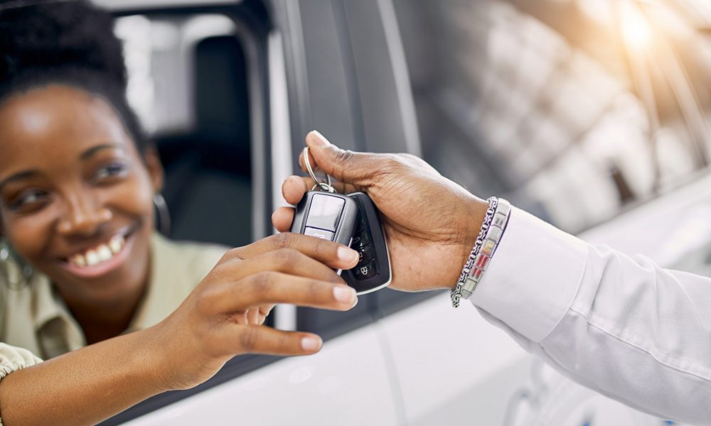 Sales person hands over car keys to buyer