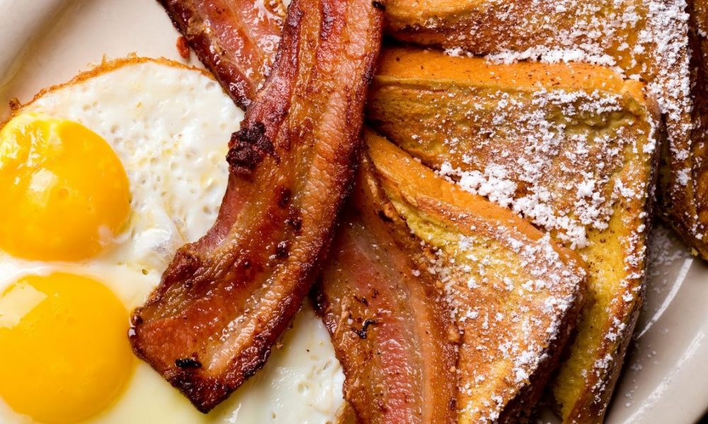 A diner breakfast of French toast, bacon and eggs over easy is shown.