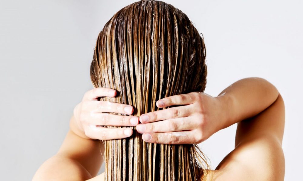 Woman applies conditioner to wet hair