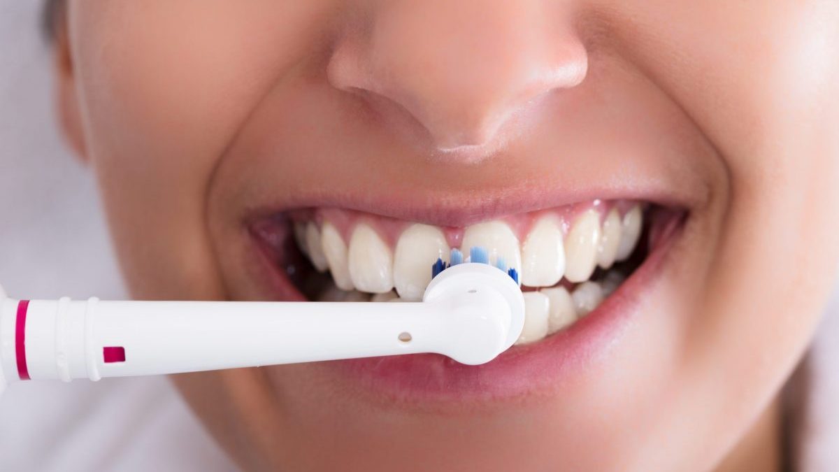 Woman brushes teeth with electric toothbrush