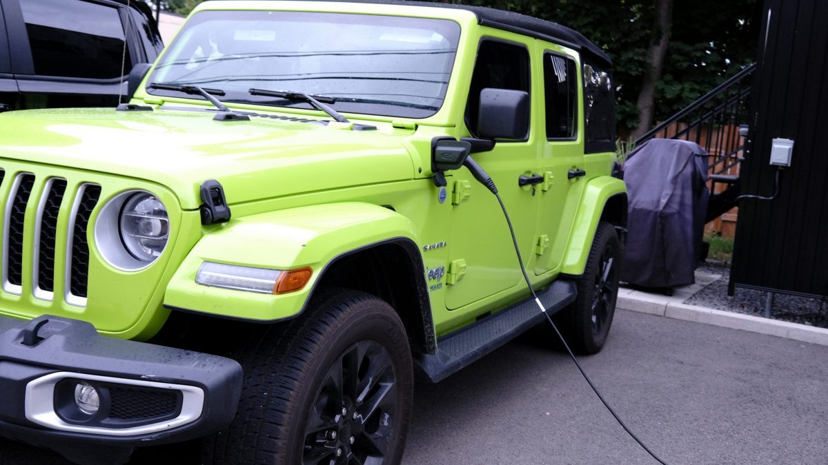 A green Jeep Wrangler 4xe is plugged in.