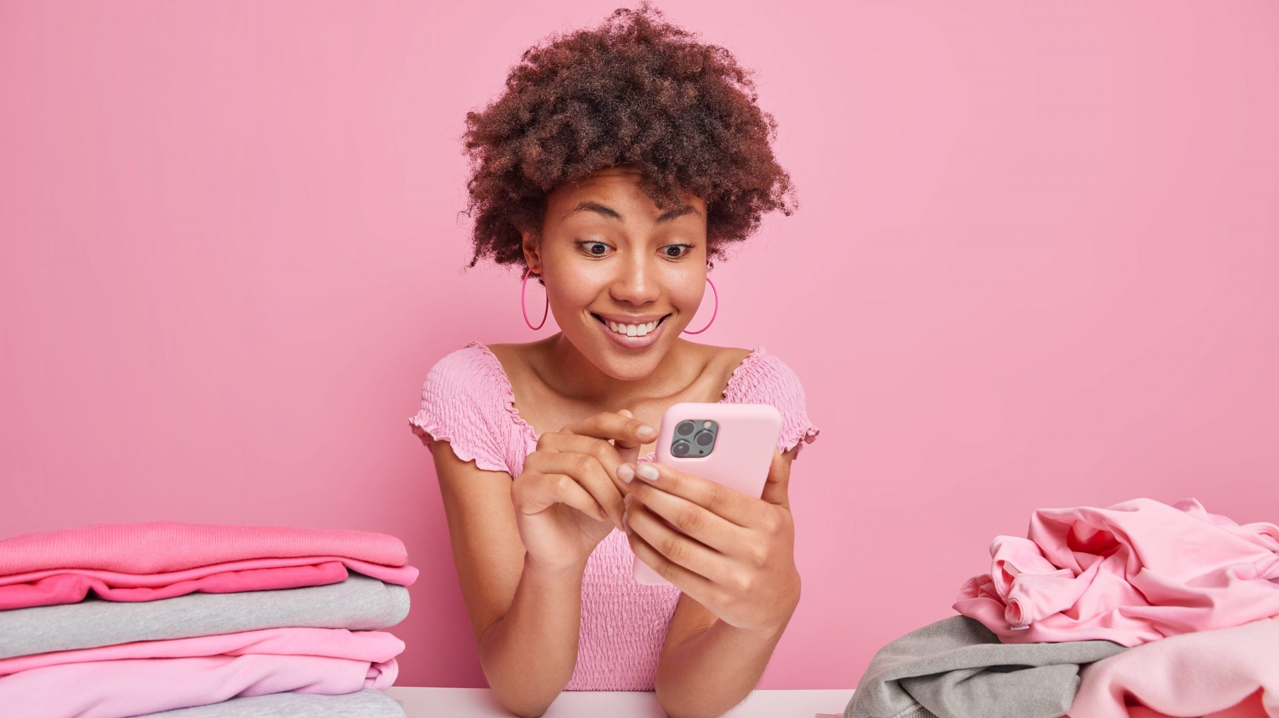 Happy woman looks at phone while doing laundry