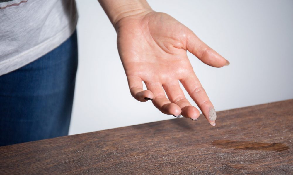 Woman swipes up dust on furniture with finger