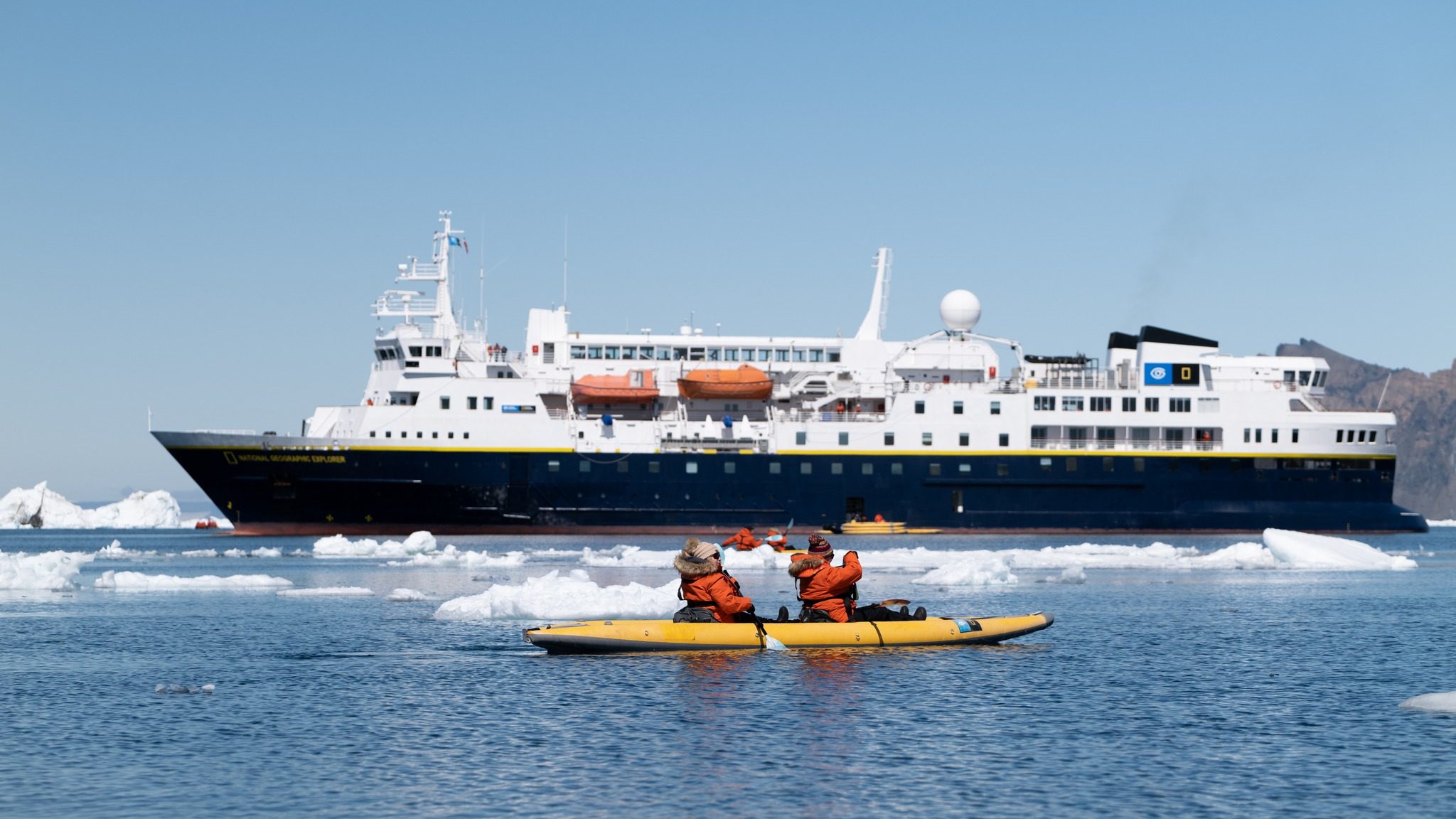 Nat Geo Explorer ship in icy sea with kayakers