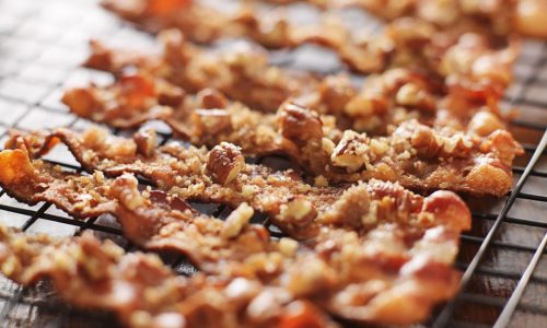 candied bacon with pecans and brown sugar cooling on baking rack