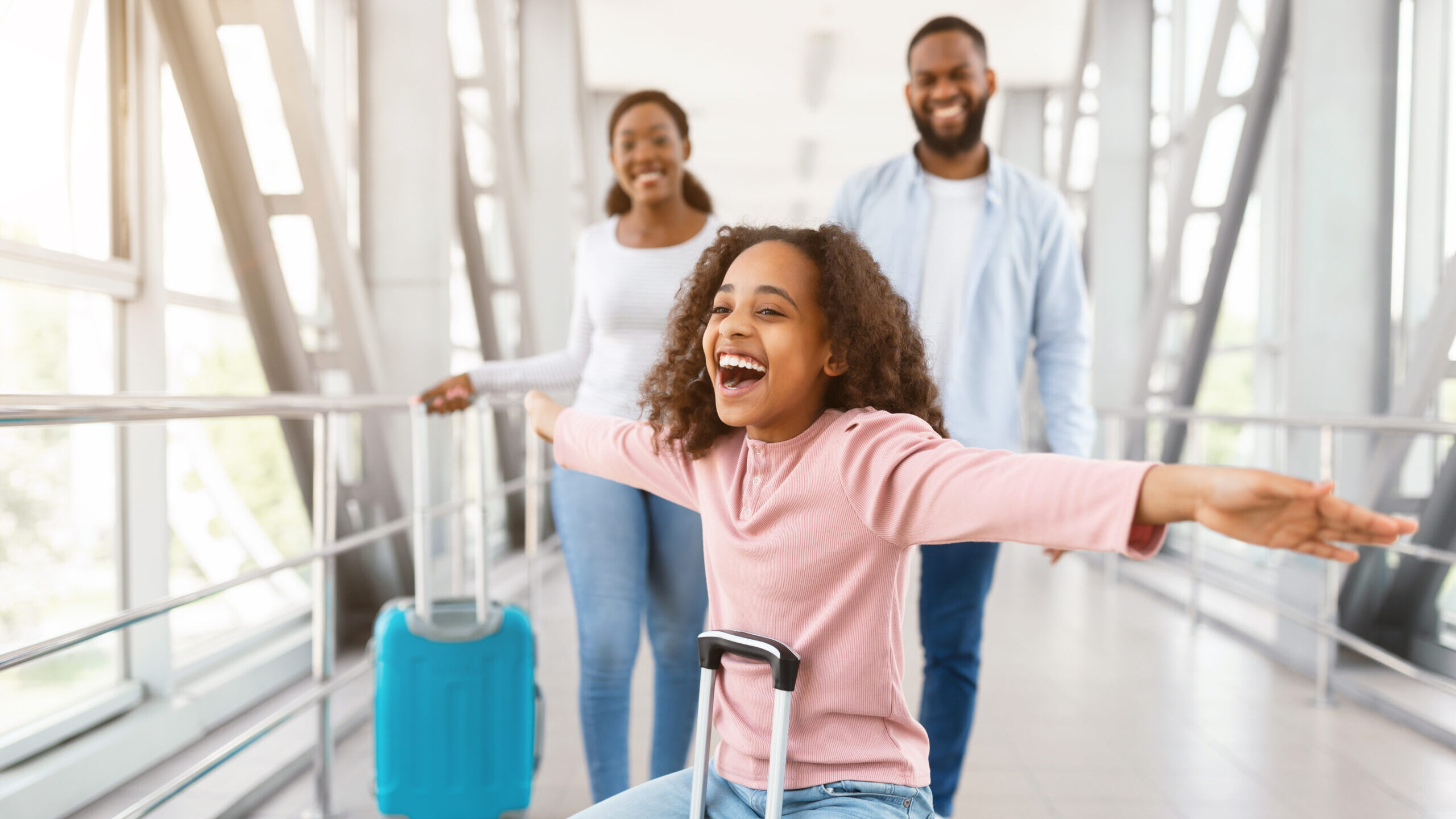 Little girl rides roller suitcase at airport