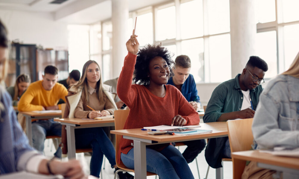 Happy student raises hand in classroom