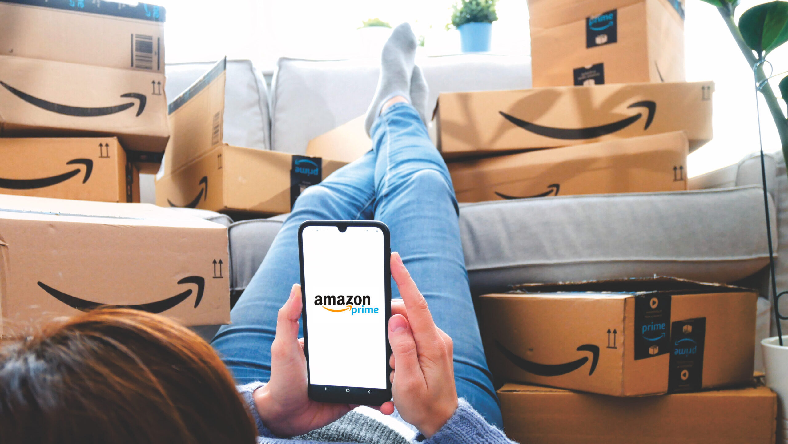 Shopper looks at Amazon app on phone, surrounded by packages