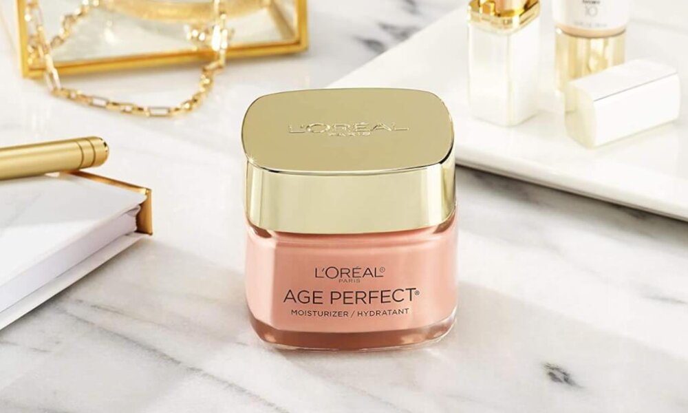 A jar of L'oreal Paris Age Perfect Rosy Tone Anti-Aging Moisturizer sits on a marble vanity.