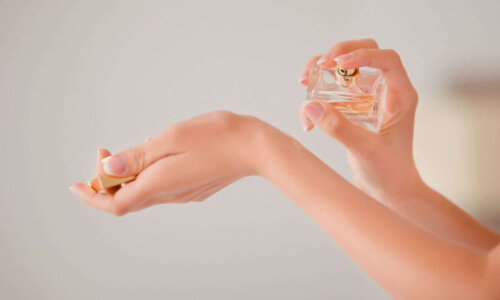 Woman putting perfume on wrist