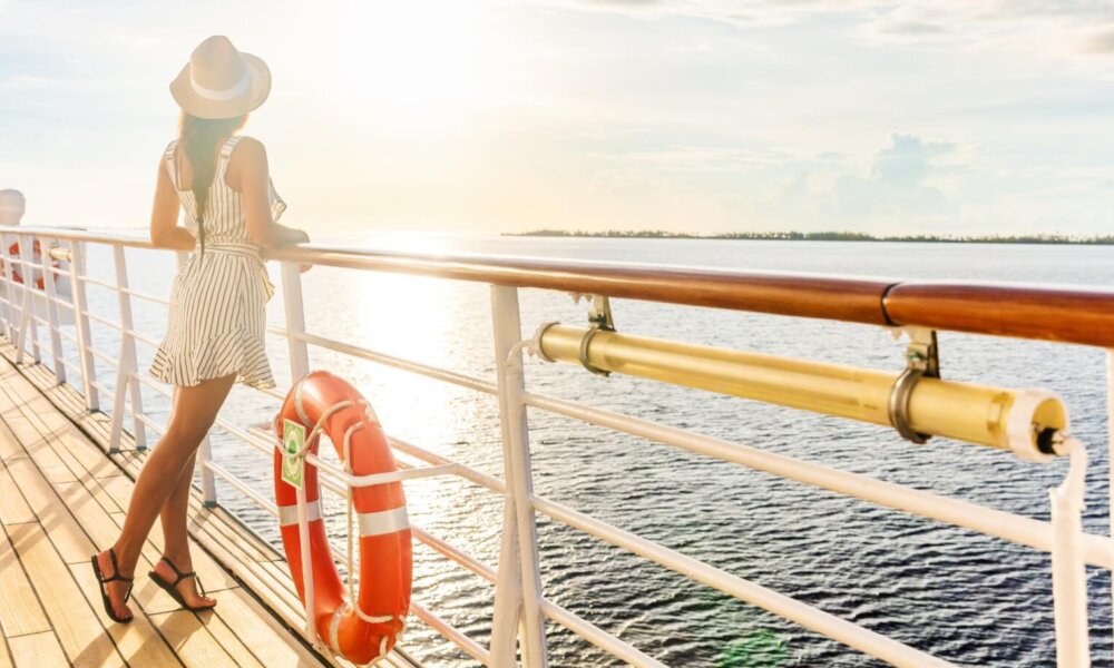 Woman looks at ocean from deck of cruise ship