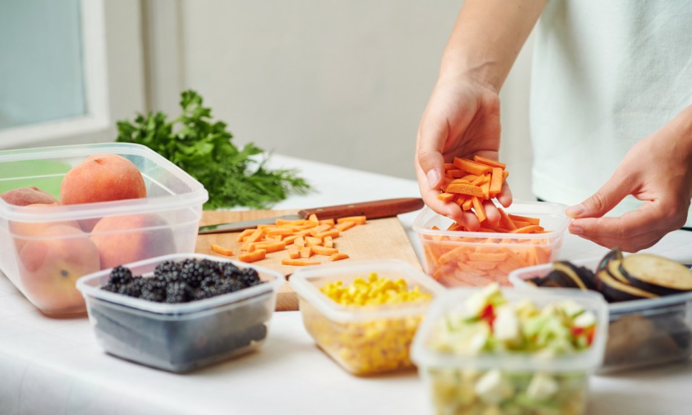 Woman putting chopped food into plastic storage containers