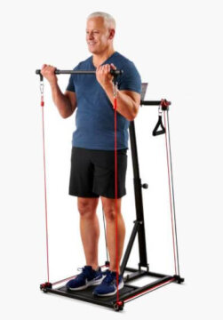 An adult man with grey hair standing up and using a Hammacher Schlemmer suspension trainer