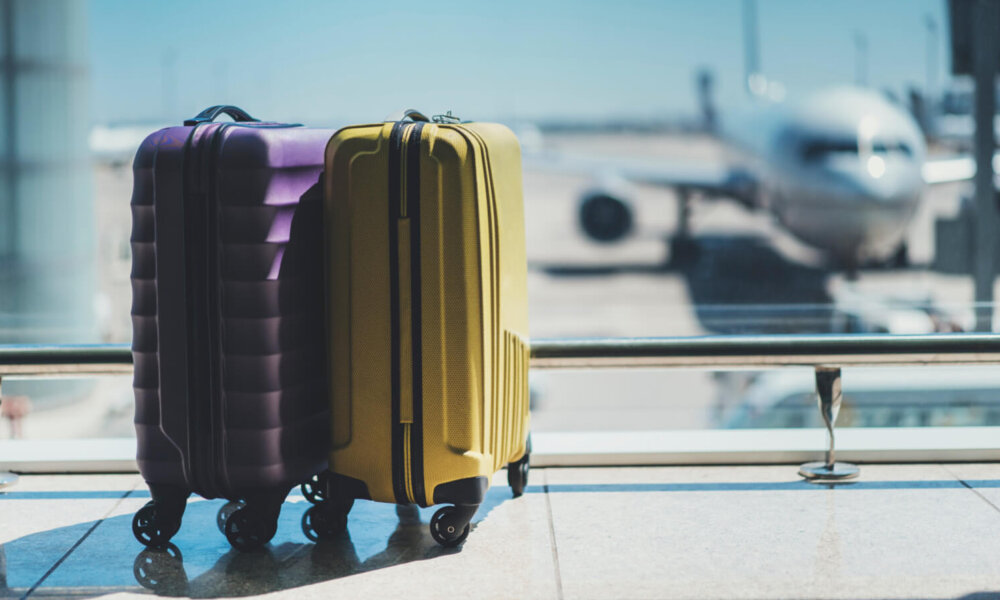 Two suitcases in an airport in front of a plane