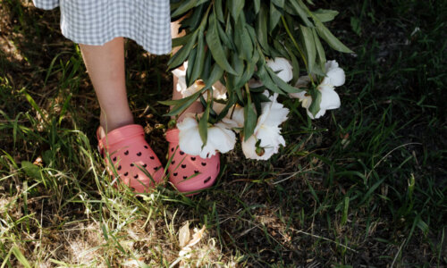 Person wearing pink Crocs holds a bunch of flowers